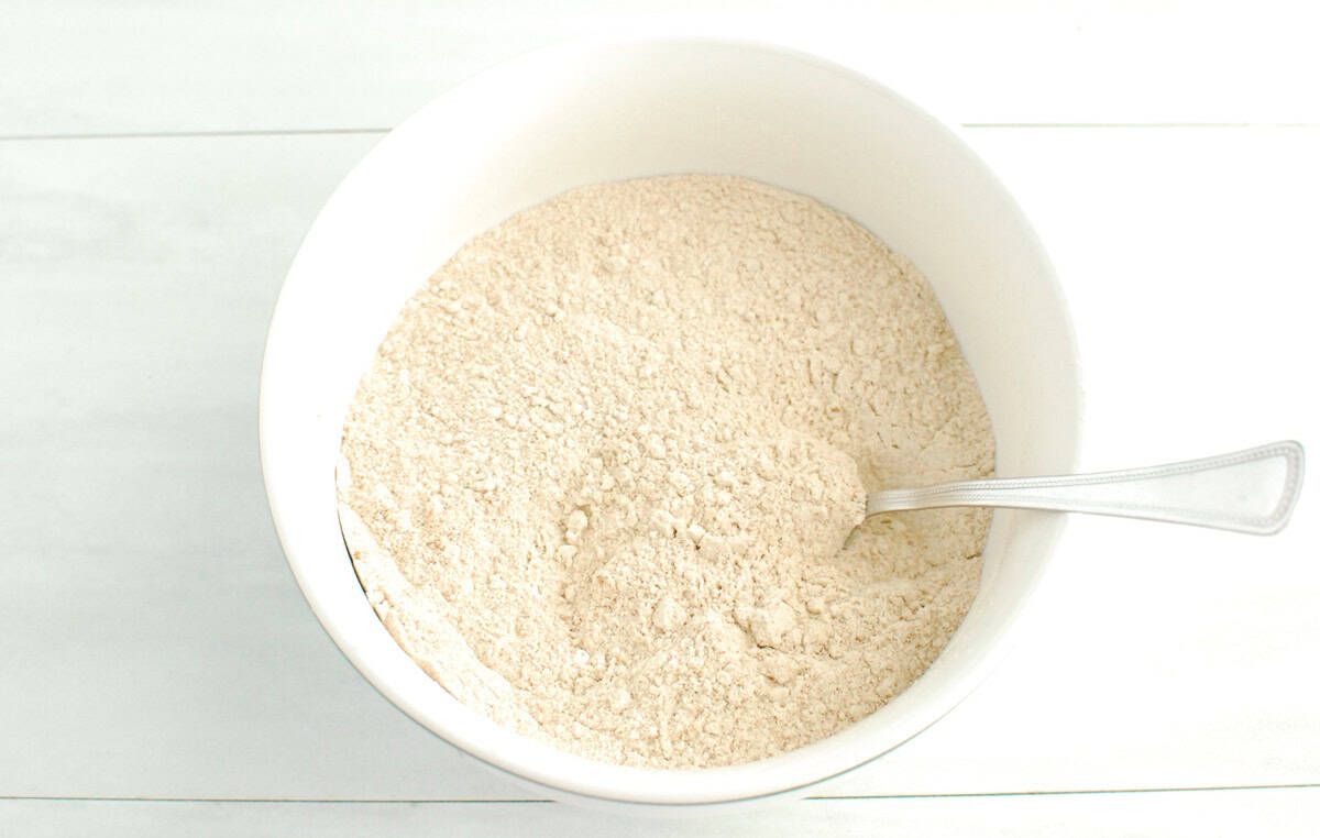 Flour, baking powder, pumpkin spice, and salt stirred together in a bowl.