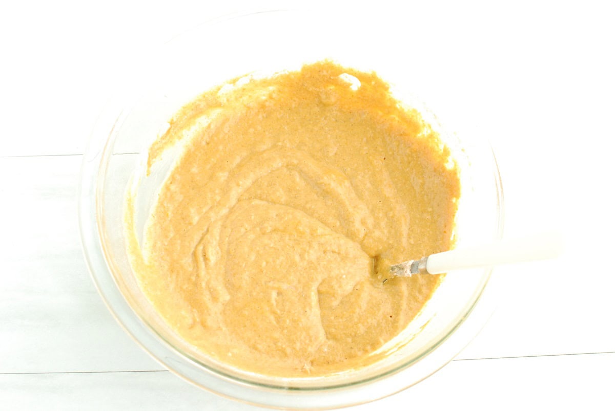 Pumpkin pancake batter in a glass mixing bowl.