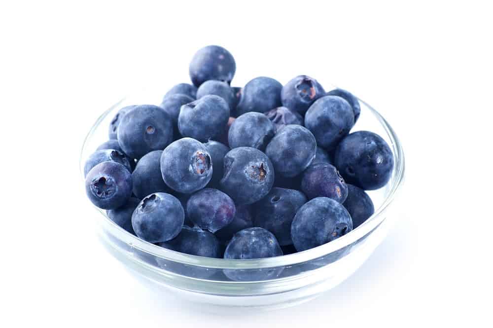 A small glass bowl full of blueberries.