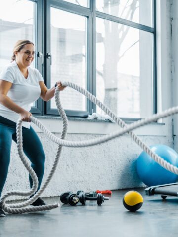A woman at the gym using battle ropes.