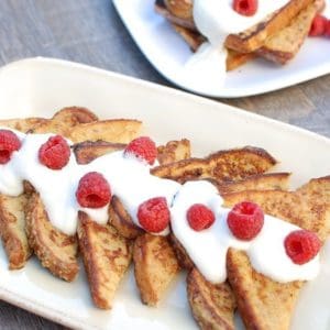 A platter with slices of eggnog french toast topped with raspberries.