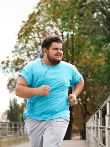 A man running along a path listening to music while training for his first half marathon.