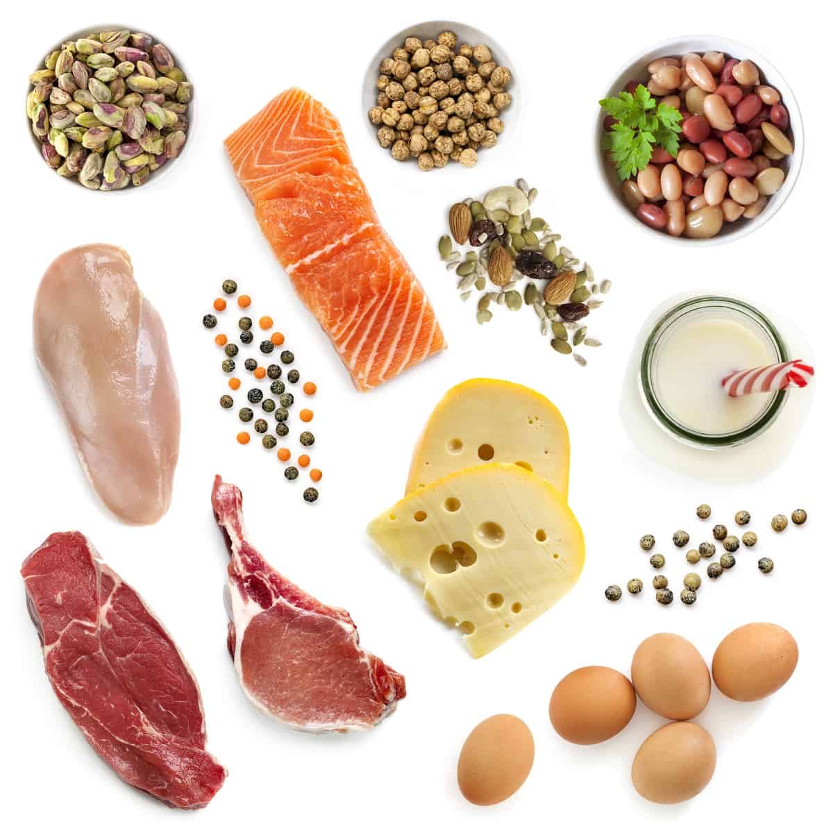 Assorted protein foods on a white backdrop including beef, chicken, fish, eggs, milk, and beans.