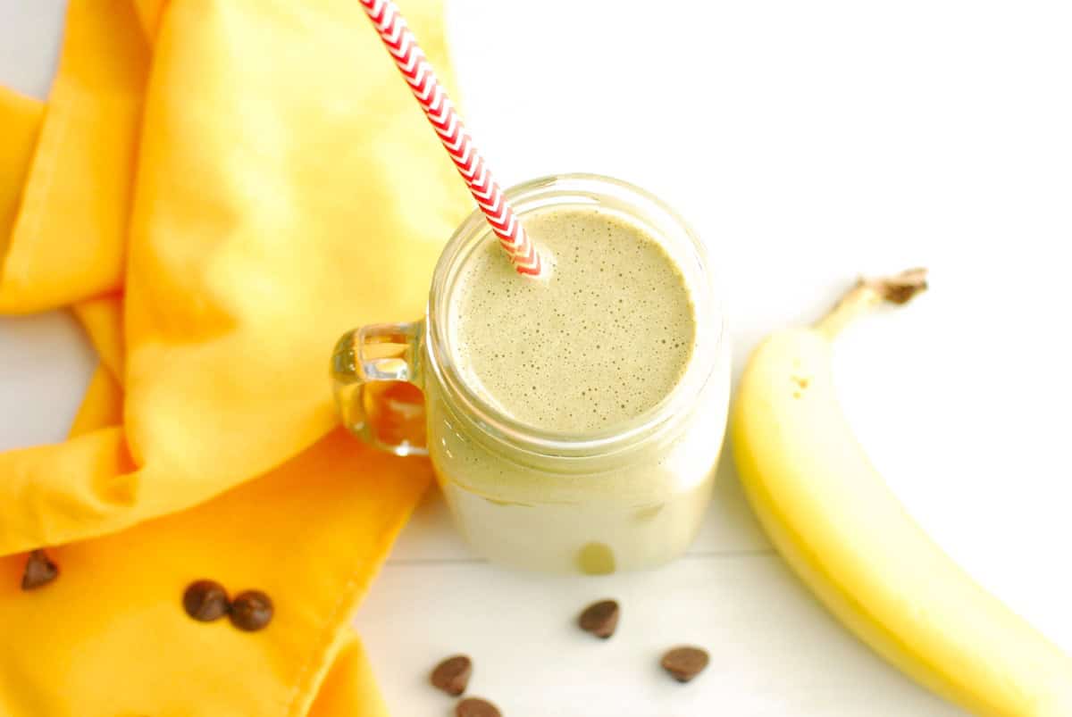 A glass jar of the post workout smoothie with a paper straw in it.