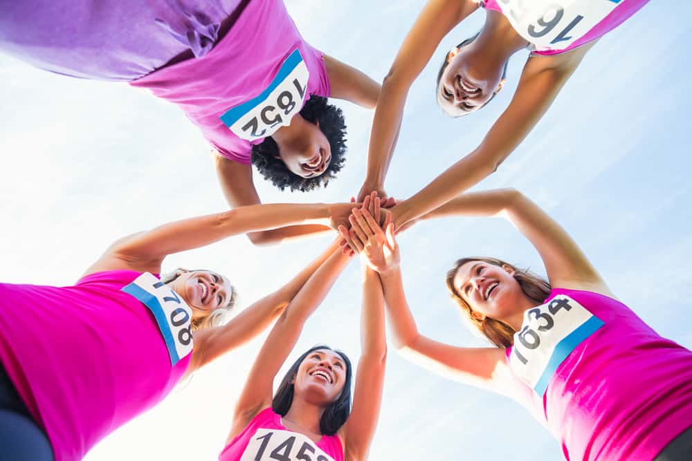 A group of female runners smiling before a race.