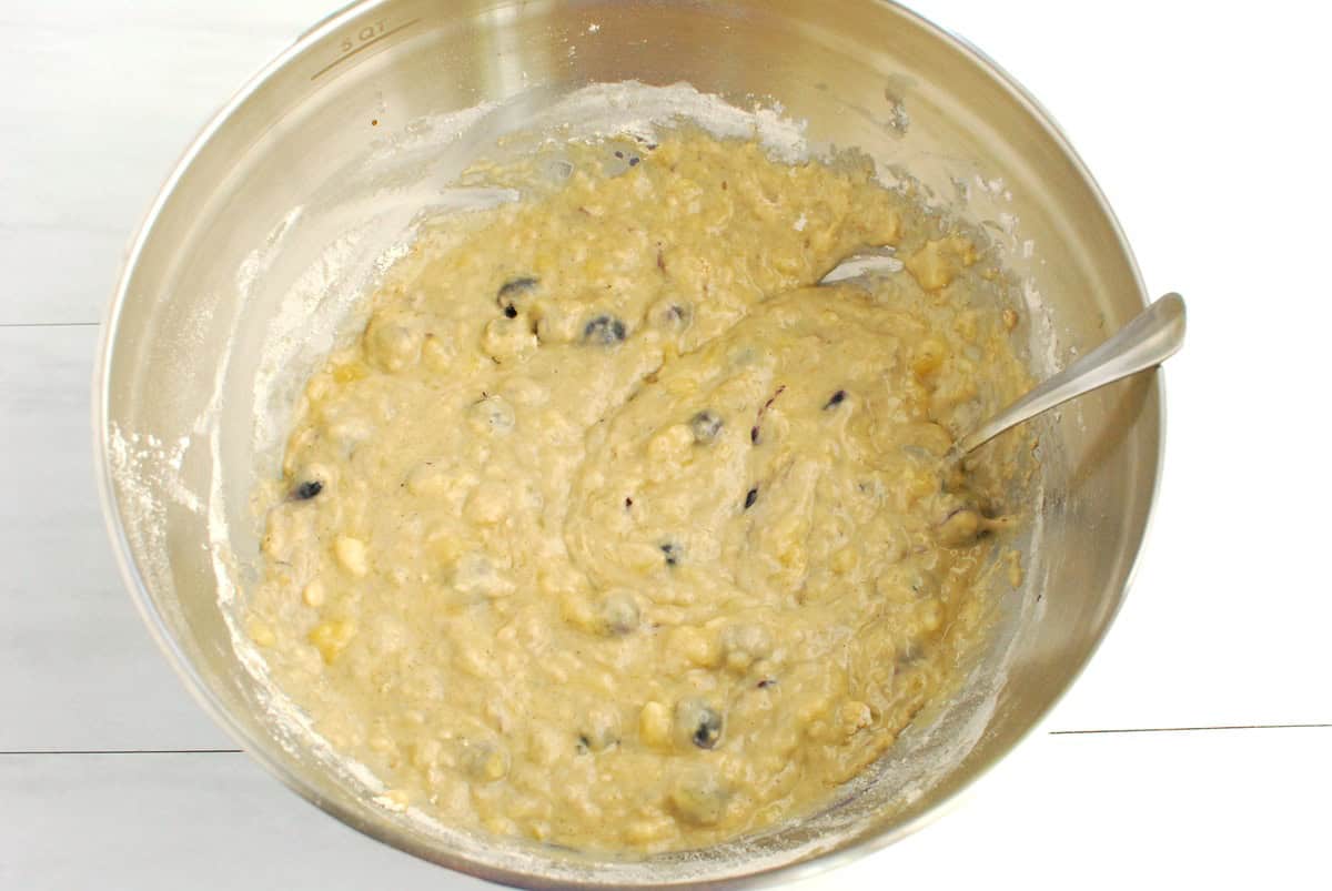 A silver mixing bowl with muffin batter.