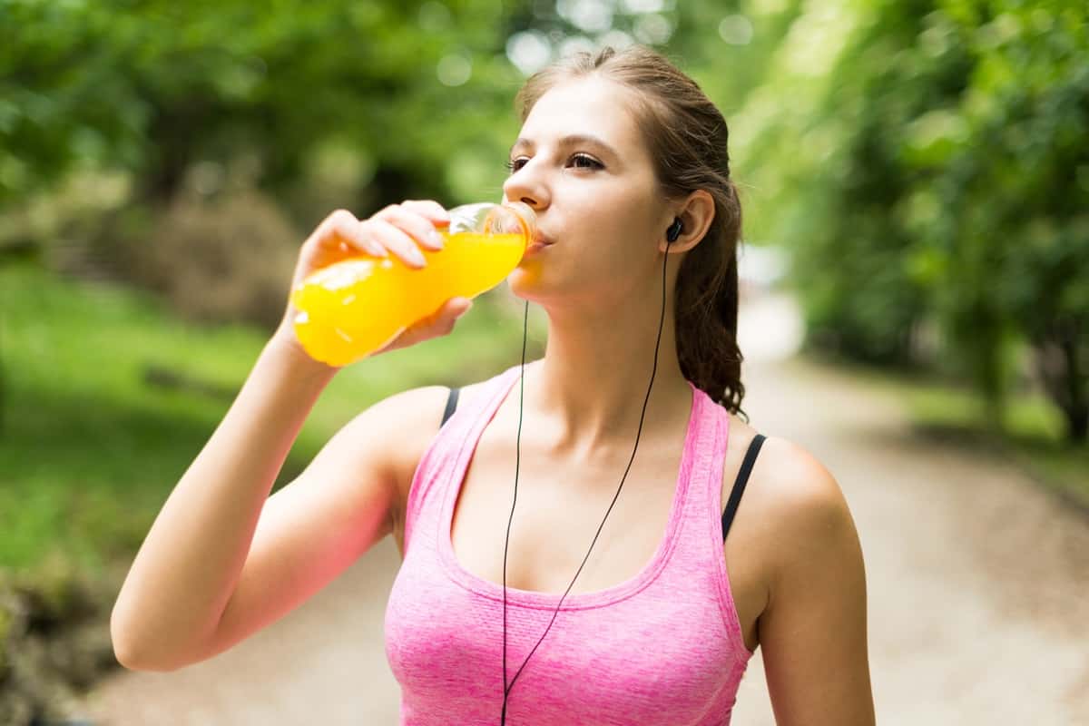 A woman drinking a sports drink before a sprint distance triathlon.