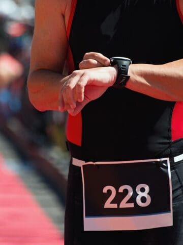 An athlete checking his watch in a sprint triathlon transition area.