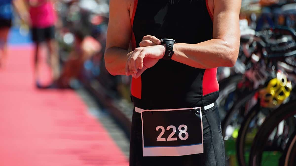 An athlete checking his watch in a sprint triathlon transition area.