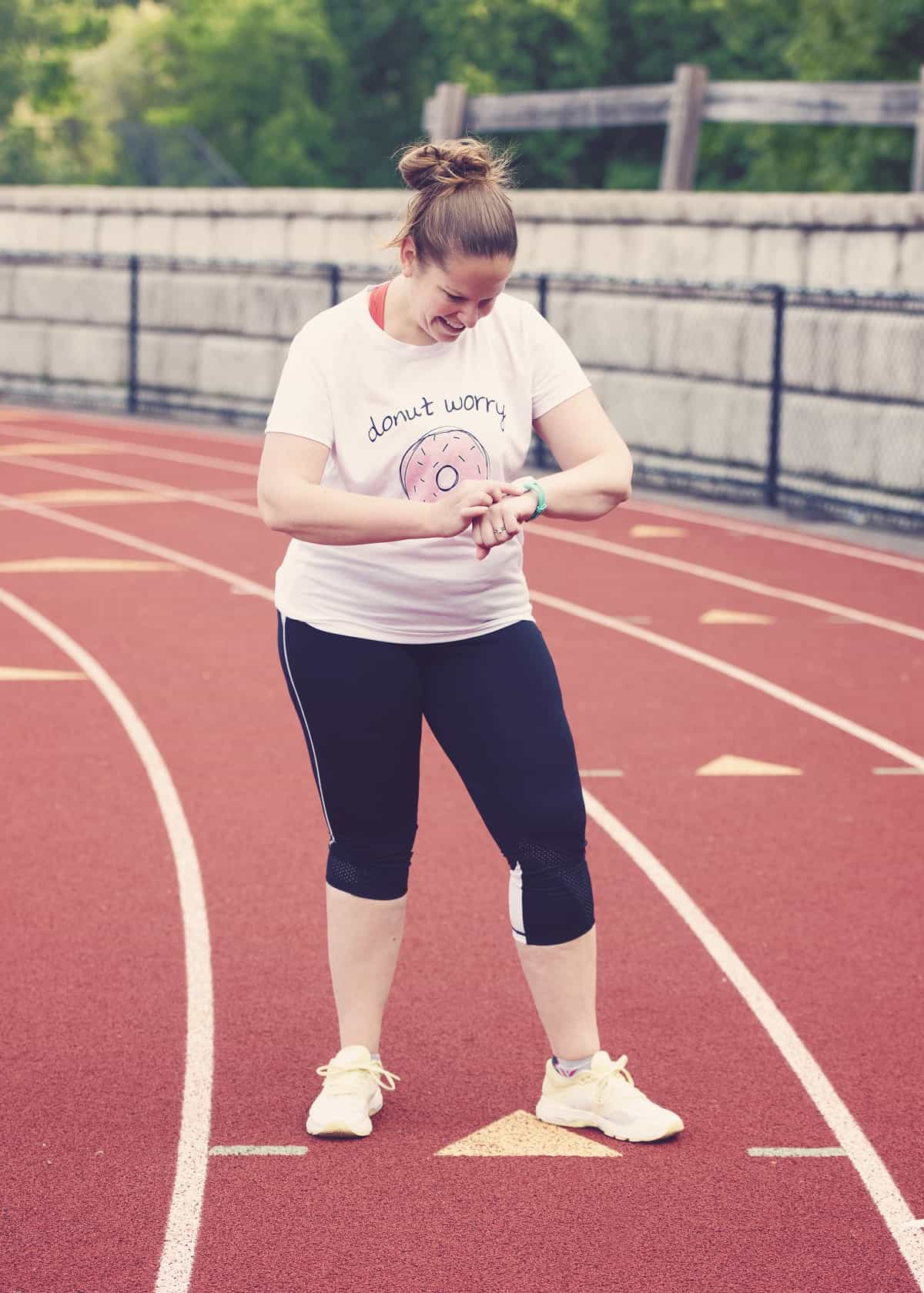 A woman checking her watch on a track.