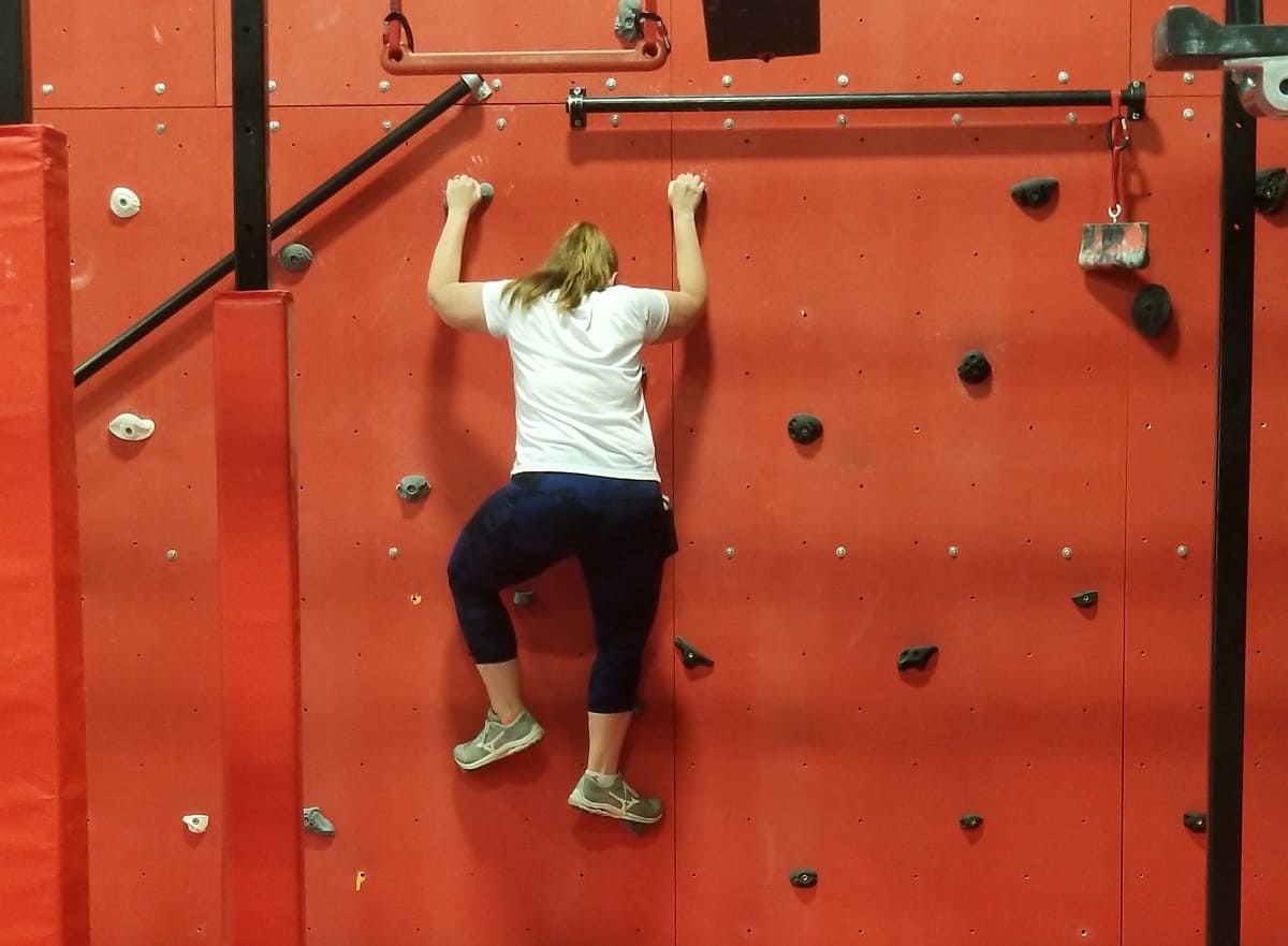 A woman on a rock climbing wall having fun working out.
