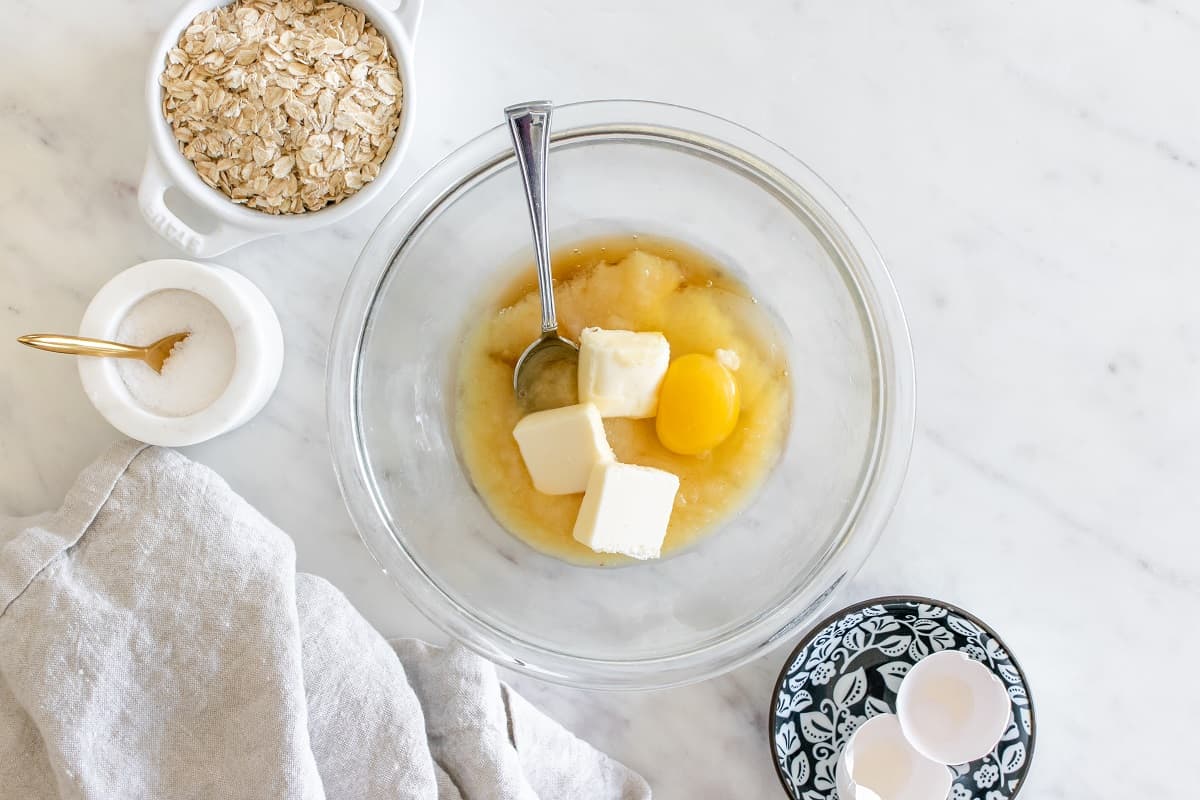 Honey, applesauce, egg, and butter in a glass mixing bowl.