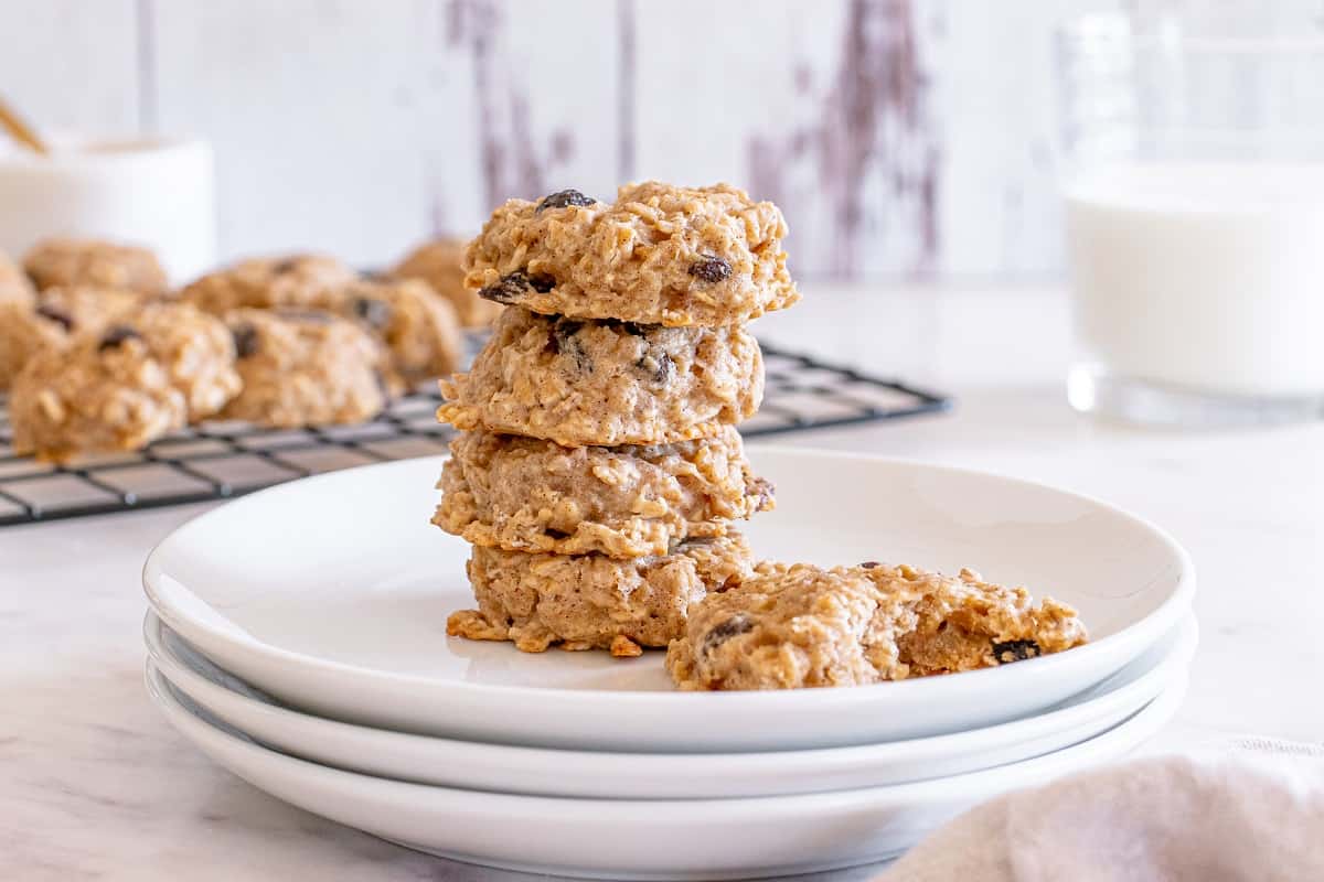 A plate with four stacked healthy oatmeal raisin cookies, and one with a bite taken out of it.