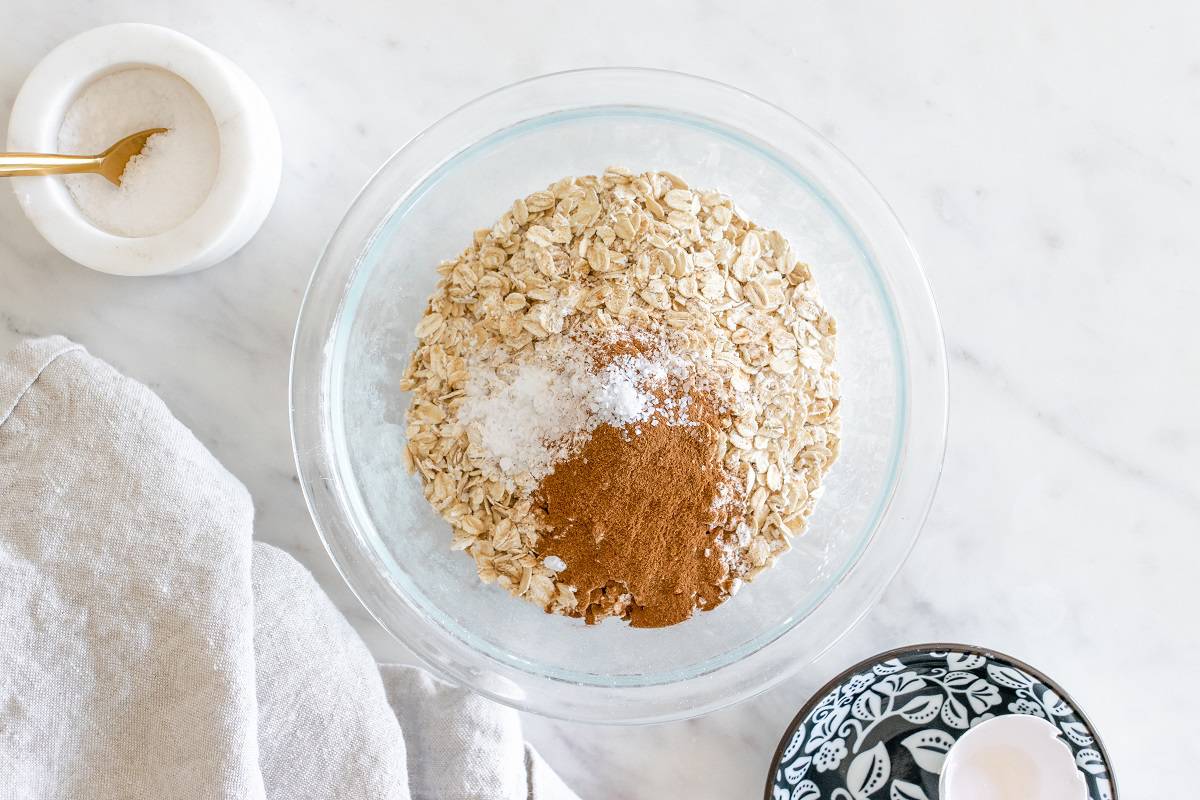 Oats, flour, baking powder, cinnamon, and salt in a glass mixing bowl.