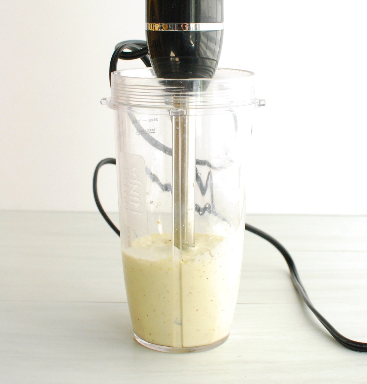Aquafaba aioli in a blender cup with an immersion blender stuck in.