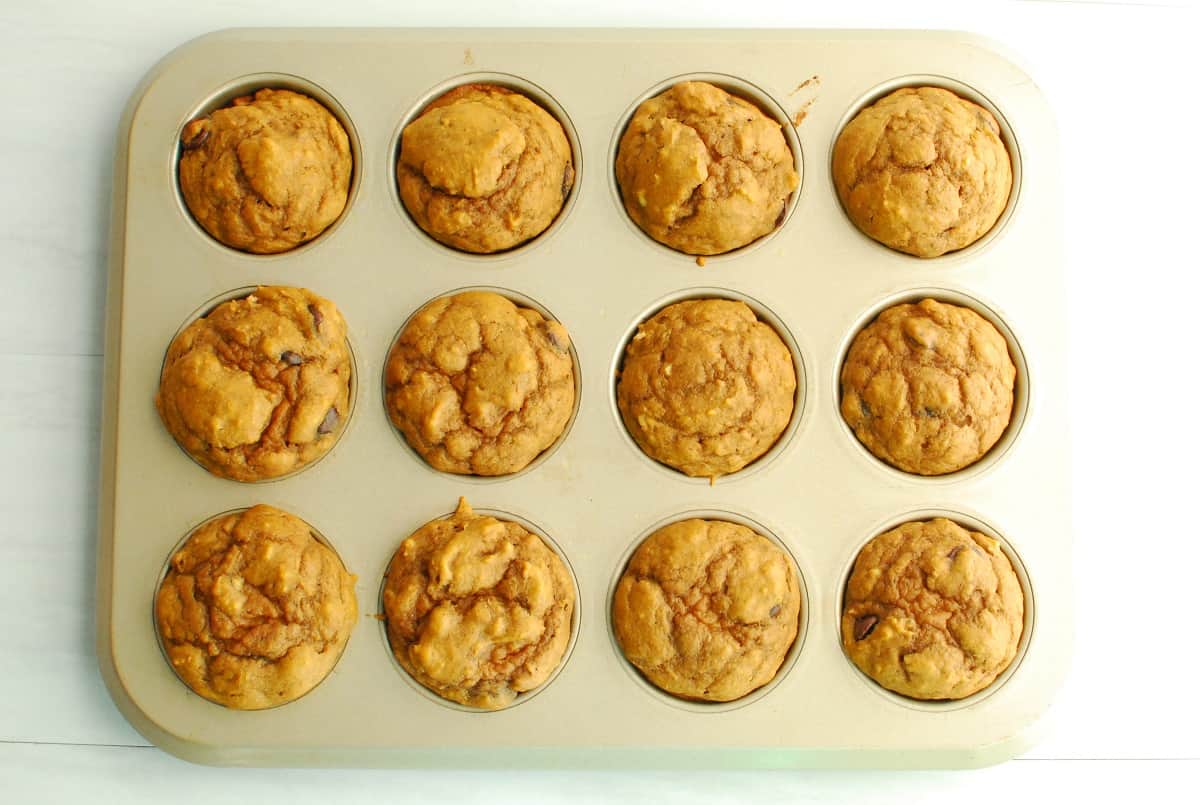 A muffin tin with freshly baked banana pumpkin muffins.