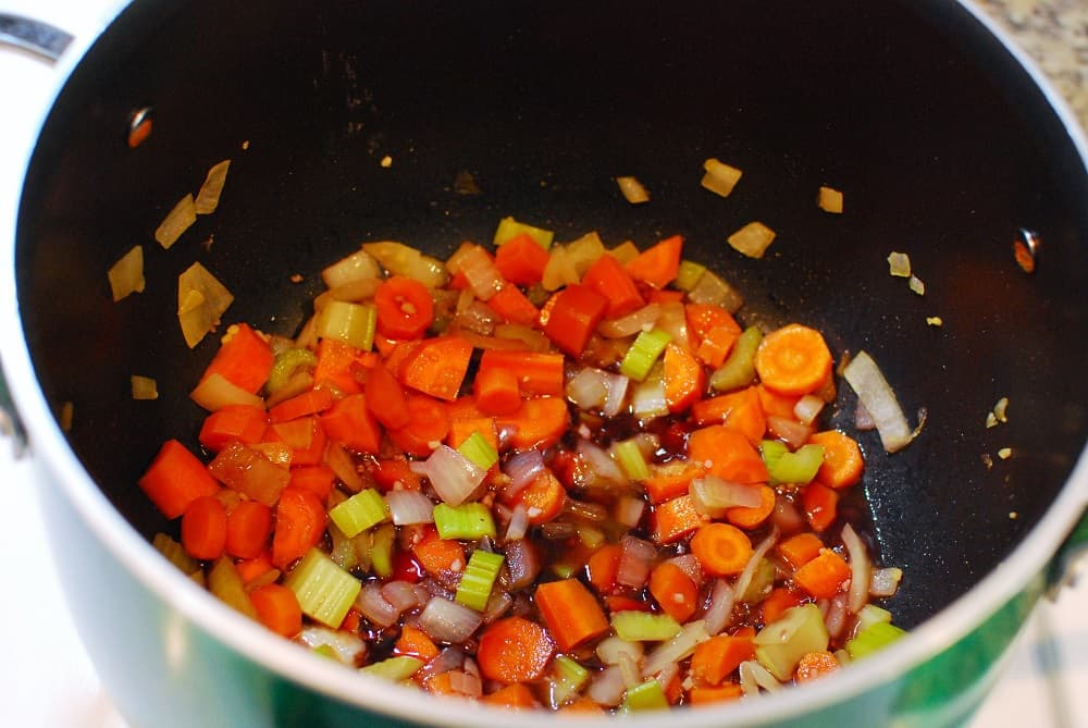 Carrots, celery, onions, and red wine in a pot.