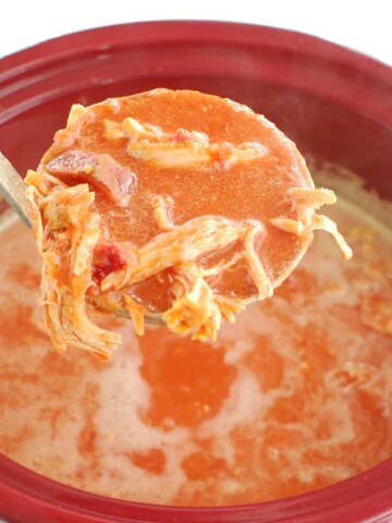 A ladle full of butternut squash beet soup over a crockpot.