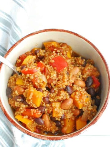 A bowl of butternut squash and quinoa chili with a spoon in the bowl.
