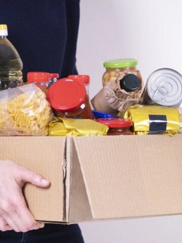 A woman holding a box of affordable food pantry donations.