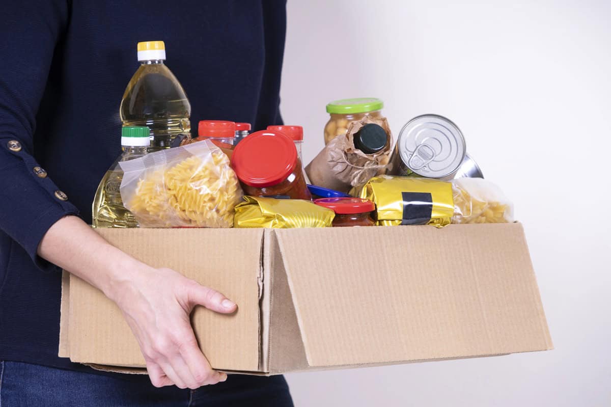 A woman holding a box of affordable food pantry donations.