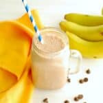A mocha banana smoothie in a glass with a straw.