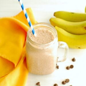 A mocha banana smoothie in a glass with a straw.