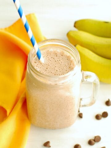 A mocha banana smoothie in a glass with a straw.