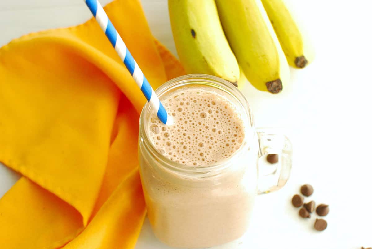 A mocha banana smoothie in a glass with a blue straw.
