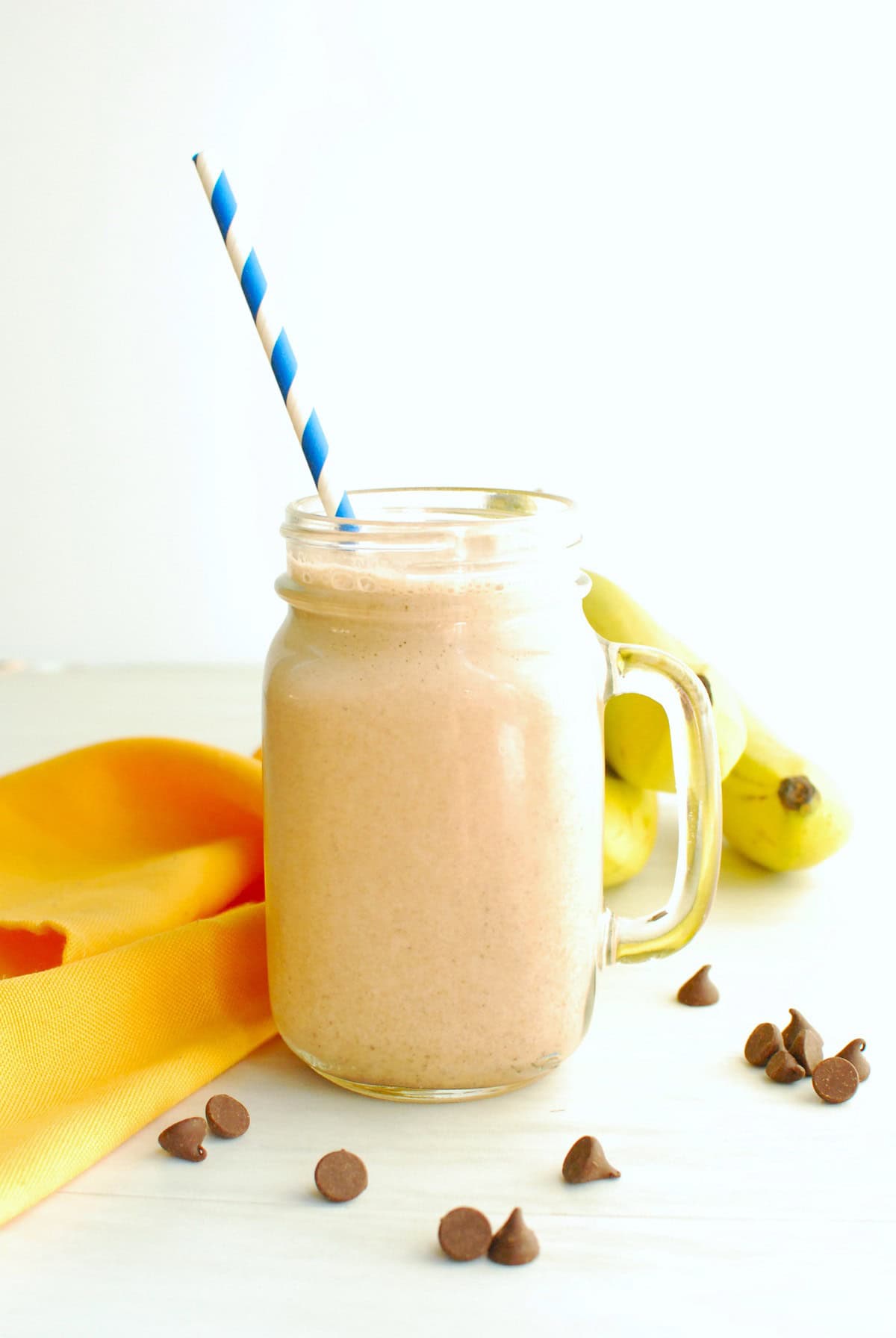 A mason jar glass of banana mocha smoothie next to a yellow napkin.