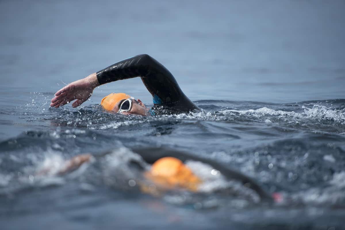 A man swimming in open water during his first triathlon.