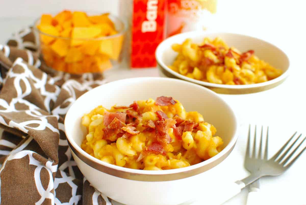 A bowl of pumpkin butternut squash pasta garnished with bacon.