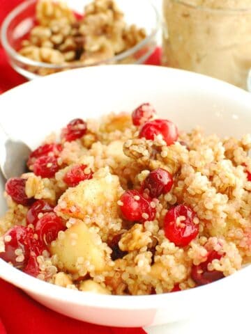 A cranberry apple quinoa breakfast bowl with a spoon in it.
