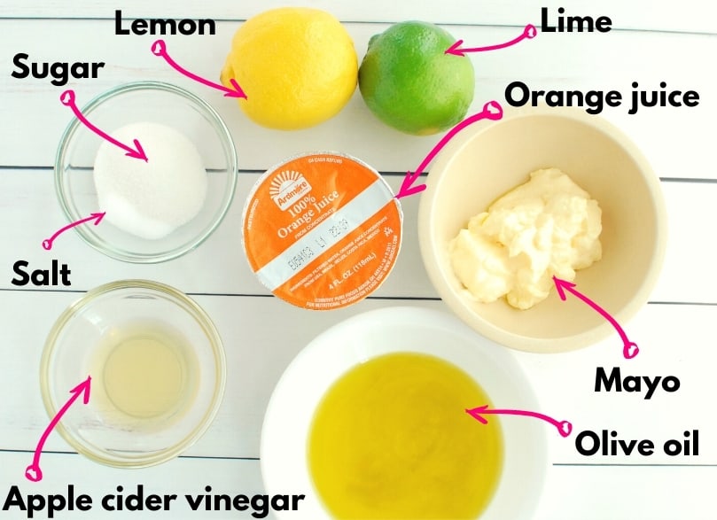 An overhead shot of all the ingredients needed for this recipe, including oil, mayo, vinegar, salt, sugar, lemon, lime, and orange juice.