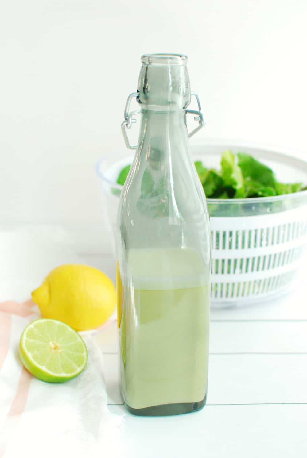 A bottle of salad dressing next to a sliced lime and a napkin.