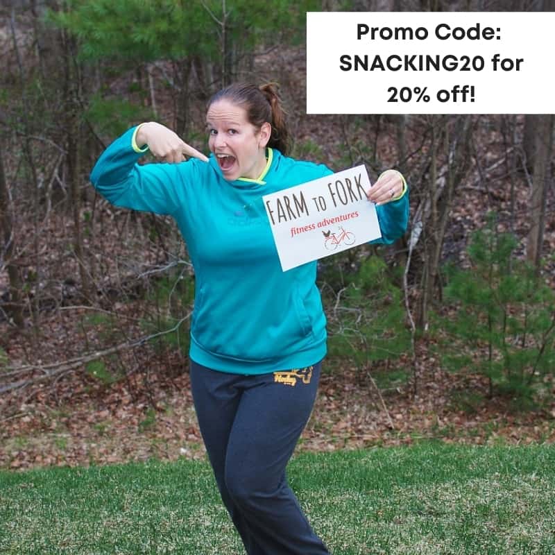 A woman holding a sign with a Farm to Fork Fondo promo code.