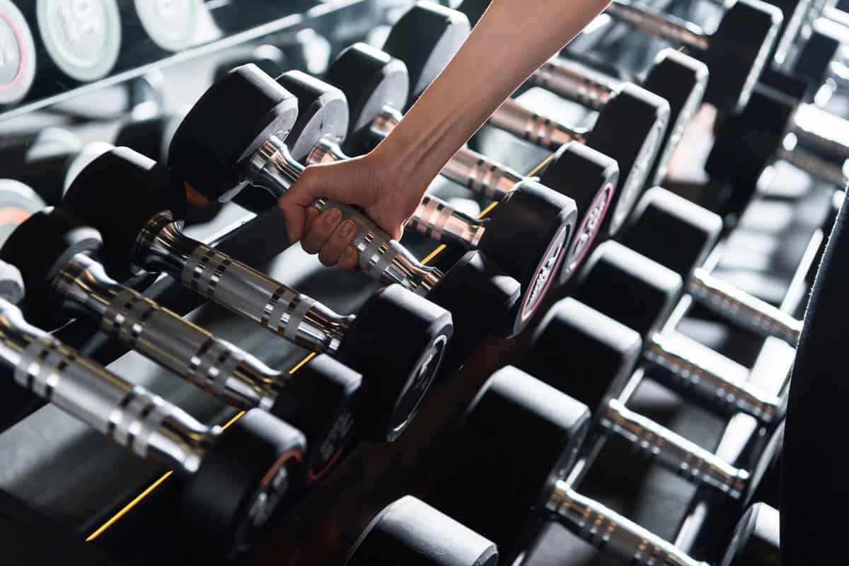 A hand grabbing a dumbbell from the rack.