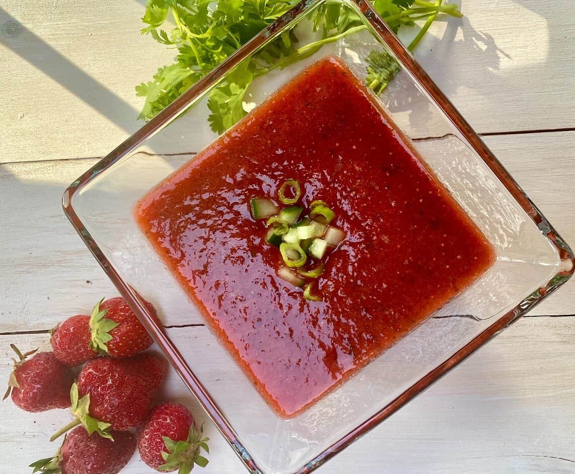 Strawberry gazpacho soup in a clear bowl.