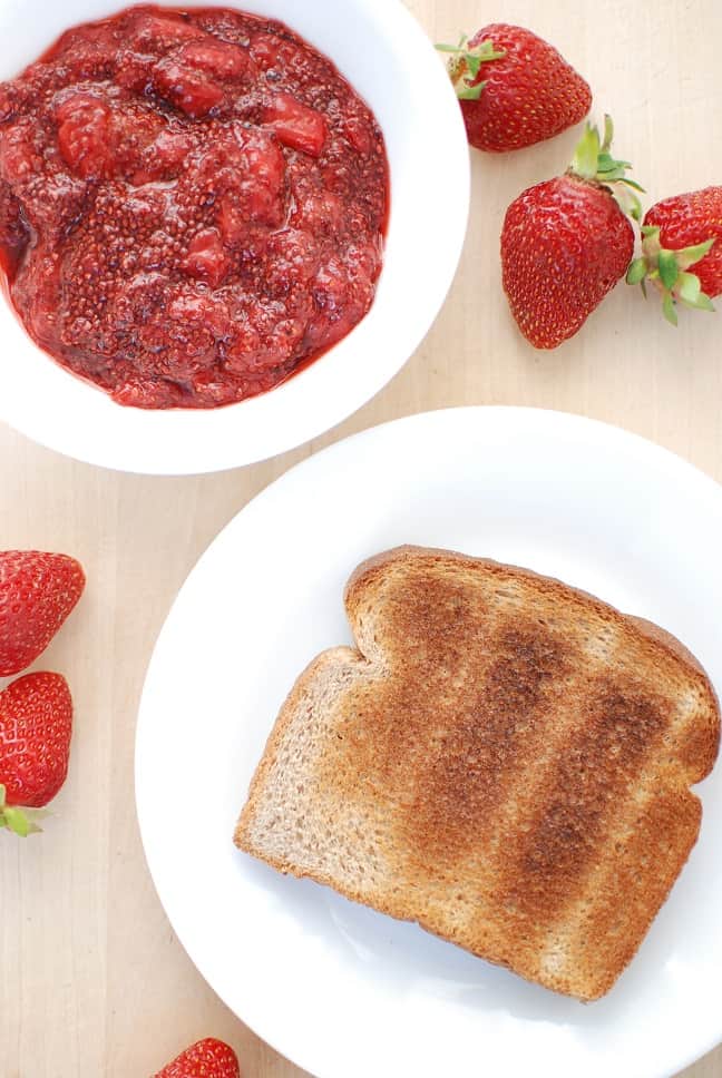 A piece of toast next to strawberry chia seed jam.