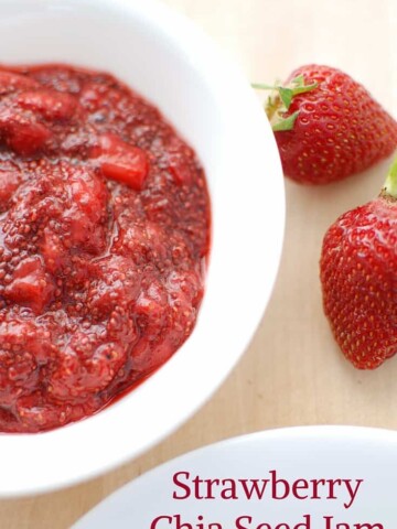 A bowl full of strawberry chia jam next to some fresh strawberries.
