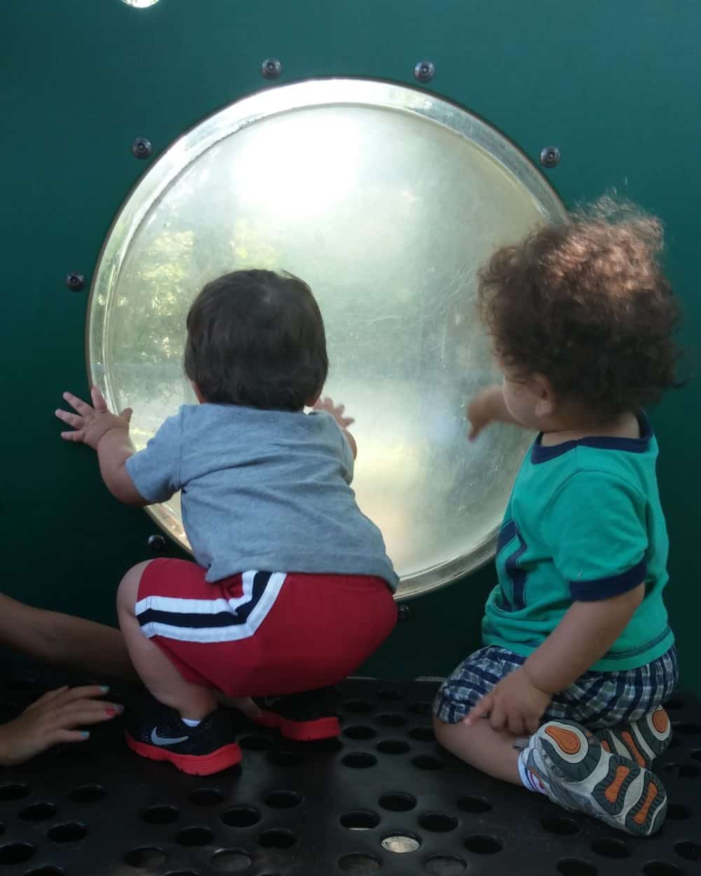 Two toddlers playing together at a playground.