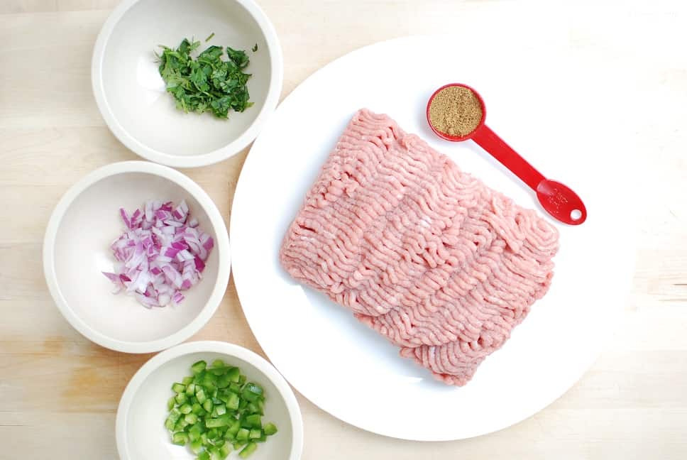 Ground turkey, cumin, cilantro, red onion, and jalapeno, ready to be used to make burgers.