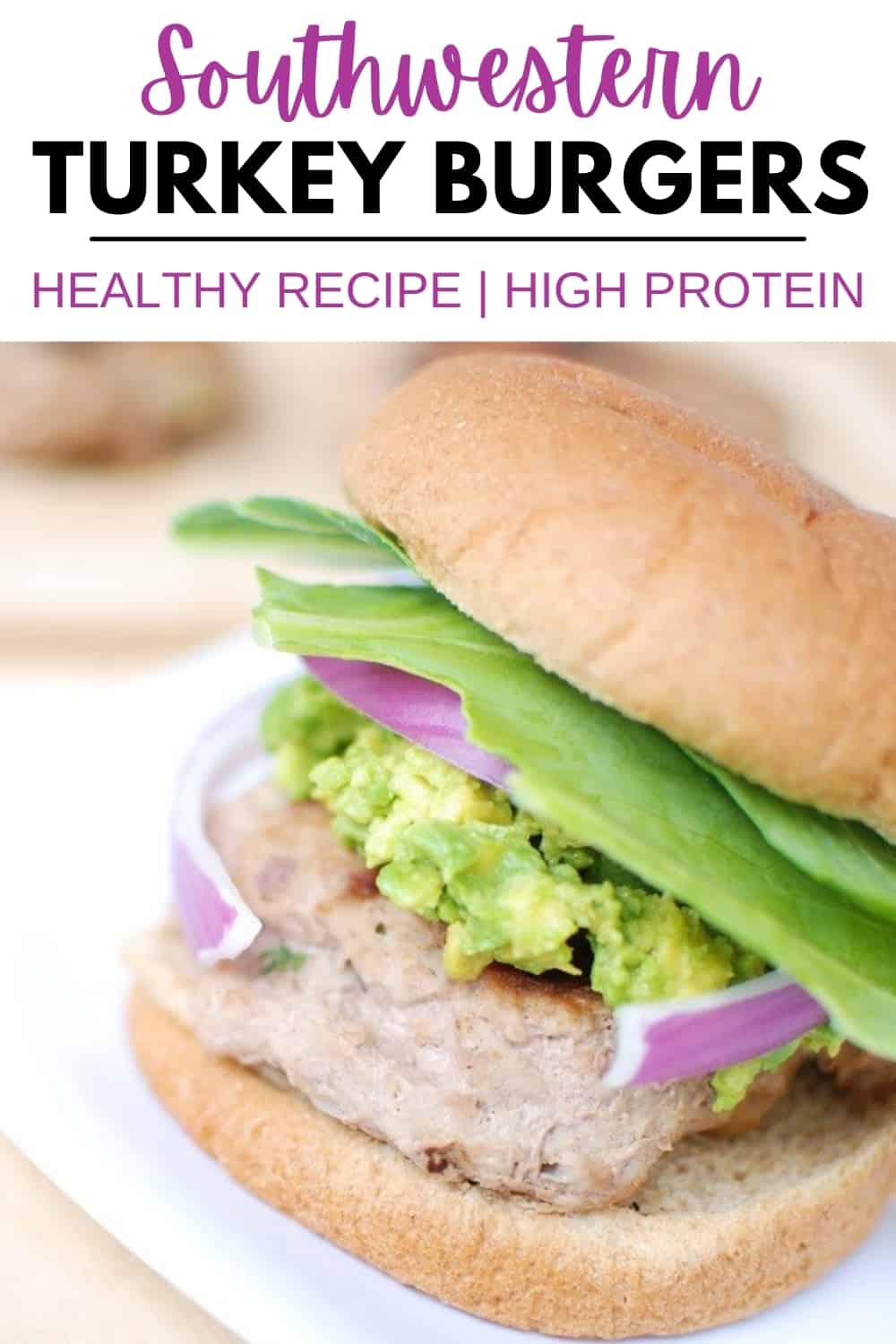 A southwestern turkey burger topped with guacamole and red onion on a whole wheat bun.