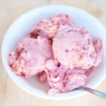 Several scoops of strawberry banana ice cream in a white bowl.
