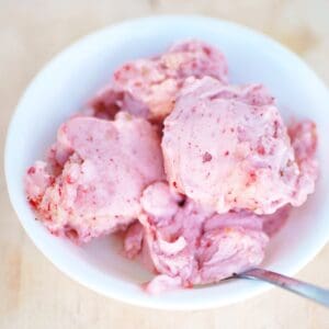 Several scoops of strawberry banana ice cream in a white bowl.