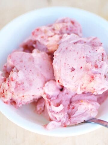 Several scoops of strawberry banana ice cream in a white bowl.