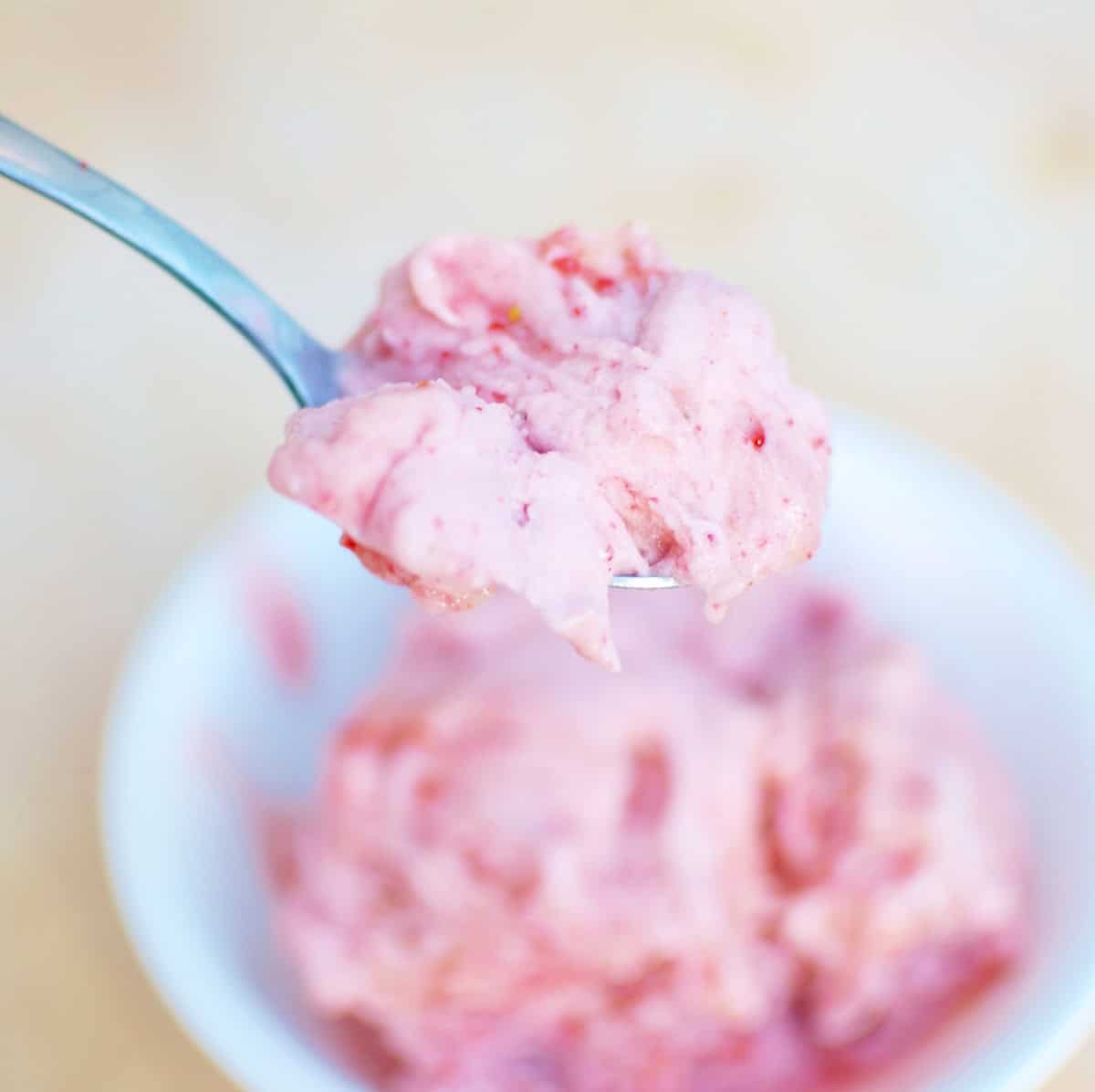 A spoon scooping out a bite of banana strawberry nice cream.