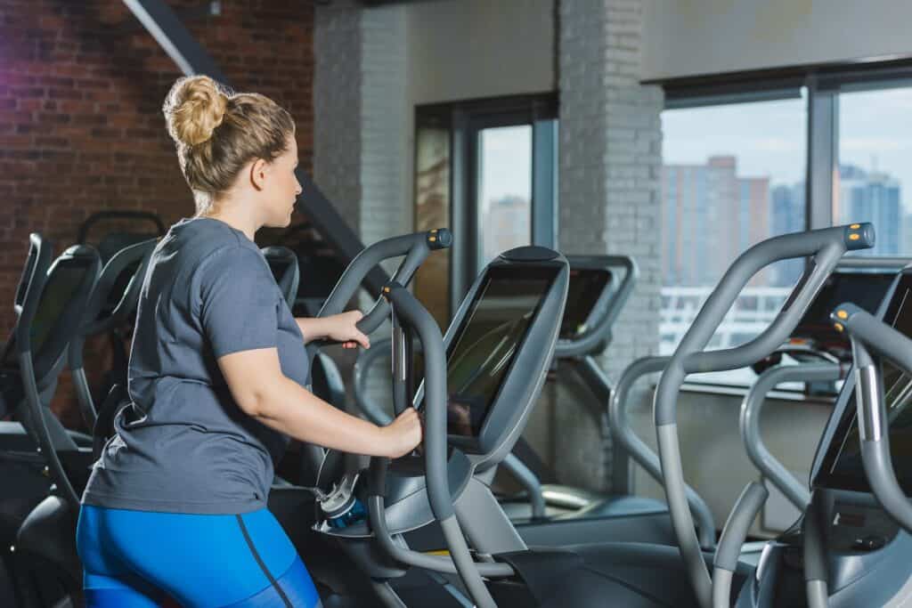 A woman on an elliptical doing cardio at a gym.