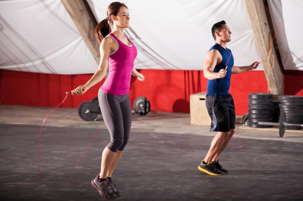 Young man and woman jumping ropes as part of their cardio workout.