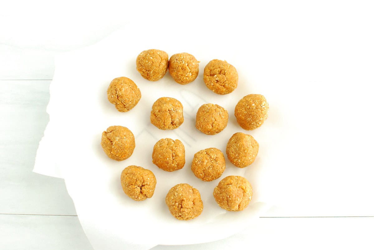 Pumpkin truffle filling rolled into balls and placed on a parchment-lined plate.